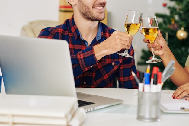 Développeur de logiciels souriant buvant du champagne avec un collègue après avoir terminé un grand projet la veille de Noël