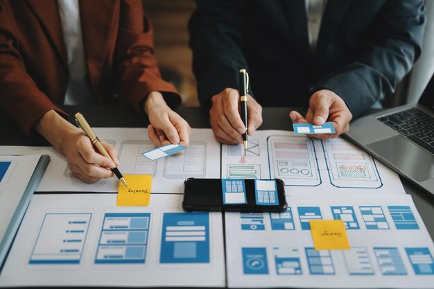 Développeur UX et concepteur d'interface utilisateur remue-méninges sur la conception filaire de l'interface de l'application mobile avec le client breif et le code couleur chez officexA