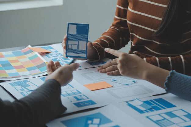 Développeur ux en gros plan et concepteur d'interface utilisateur remue-méninges sur la conception filaire de l'interface d'application mobile sur table avec breif client et code couleur au bureau moderneAgence de développement numérique créative