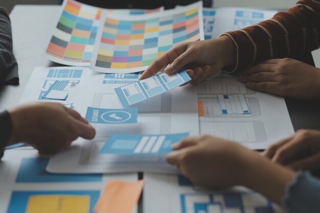 Développeur ux en gros plan et concepteur d'interface utilisateur remue-méninges sur la conception filaire de l'interface d'application mobile sur table avec breif client et code couleur au bureau moderneAgence de développement numérique créative
