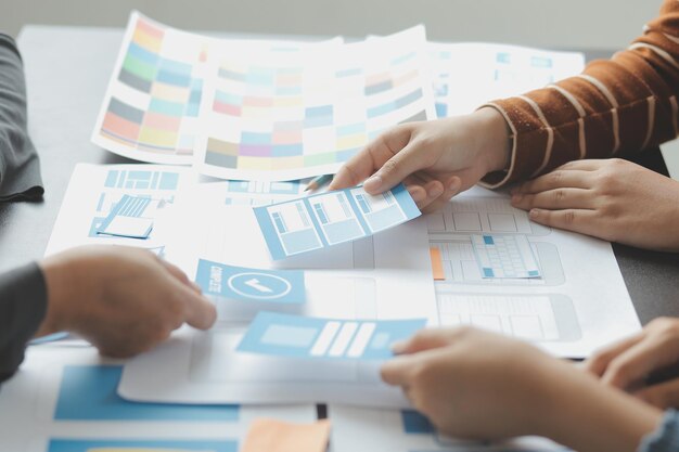 Développeur ux en gros plan et concepteur d'interface utilisateur remue-méninges sur la conception filaire de l'interface d'application mobile sur table avec breif client et code couleur au bureau moderneAgence de développement numérique créative
