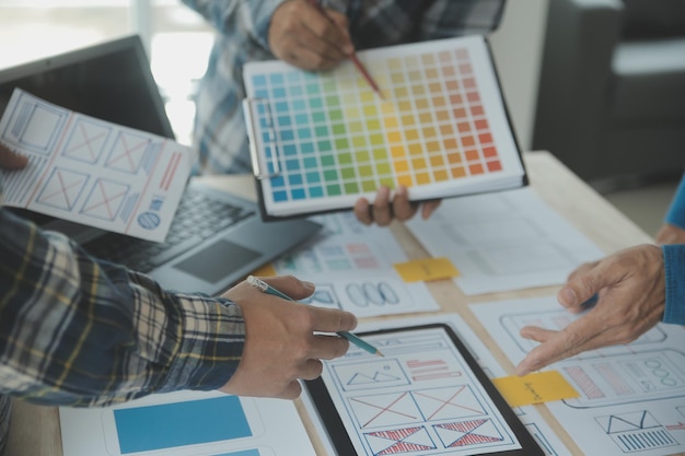 Développeur ux en gros plan et concepteur d'interface utilisateur remue-méninges sur la conception filaire de l'interface d'application mobile sur table avec breif client et code couleur au bureau moderneAgence de développement numérique créative