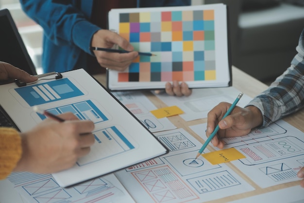 Développeur ux en gros plan et concepteur d'interface utilisateur remue-méninges sur la conception filaire de l'interface d'application mobile sur table avec breif client et code couleur au bureau moderneAgence de développement numérique créative