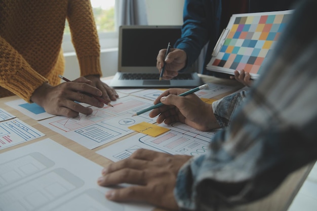 Développeur ux en gros plan et concepteur d'interface utilisateur remue-méninges sur la conception filaire de l'interface d'application mobile sur table avec breif client et code couleur au bureau moderneAgence de développement numérique créative