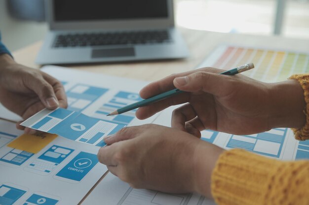 Développeur ux en gros plan et concepteur d'interface utilisateur remue-méninges sur la conception filaire de l'interface d'application mobile sur table avec breif client et code couleur au bureau moderneAgence de développement numérique créative