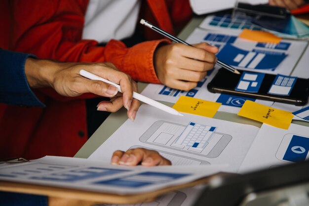 Développeur ux en gros plan et concepteur d'interface utilisateur remue-méninges sur la conception filaire de l'interface d'application mobile sur table avec breif client et code couleur au bureau moderneAgence de développement numérique créative