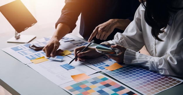Développeur ux en gros plan et concepteur d'interface utilisateur remue-méninges sur la conception filaire de l'interface d'application mobile sur table avec breif client et code couleur au bureau moderneAgence de développement numérique créative