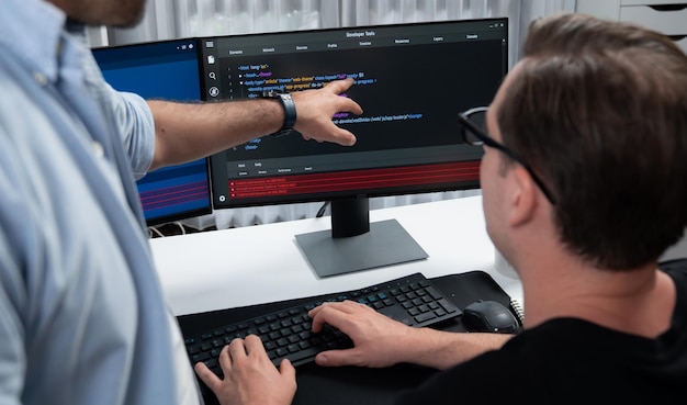 Développeurs informatiques pointant sur des informations de développement de logiciels sur deux écrans avec un programme de codage dans l'application et le site Web Ingénieur technique codeur analysant dans le concept de programme de sécurité Vendeur