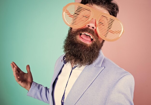 Devenir fou Homme d'affaires espiègle appréciant la fête Homme barbu portant des lunettes de fête Hipster drôle dans des lunettes extravagantes accessoire de mode Homme de mode avec une longue barbe en tenue de soirée