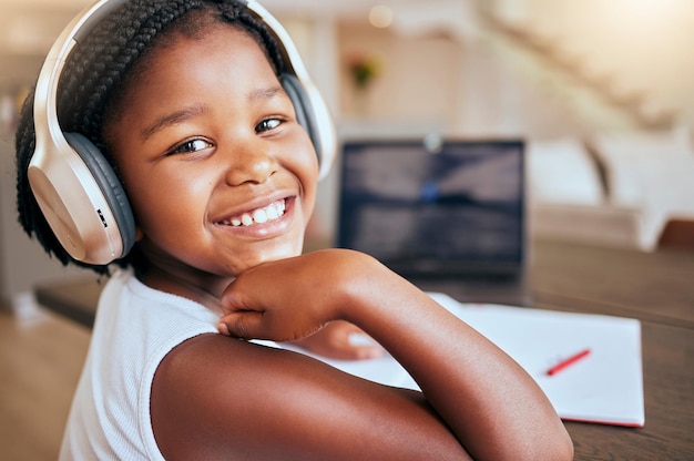 Devoirs d'éducation et fille africaine avec de la musique pour apprendre à étudier et à apprendre en ligne avec des livres scolaires dans la maison Podcast heureux et portrait d'un jeune enfant avec un casque pendant l'étude de la connaissance