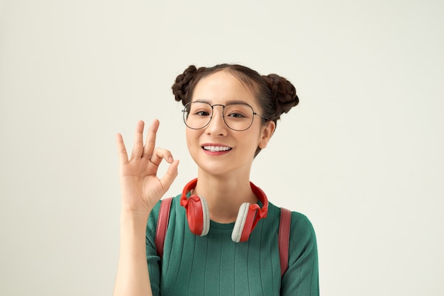 Les devoirs, c'est facile ! Une fille de lecteur douce et mignonne montre un signe ok dans les mains avec un sac à dos isolé sur fond blanc