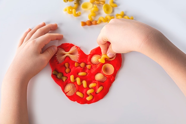 Dextérité. Créativité des enfants. Modélisation de la pâte à modeler pour le développement de l'enfant à la maison. Childs mains créant le cœur de la pâte pour la modélisation. Jeu anti-stress aux pâtes sèches