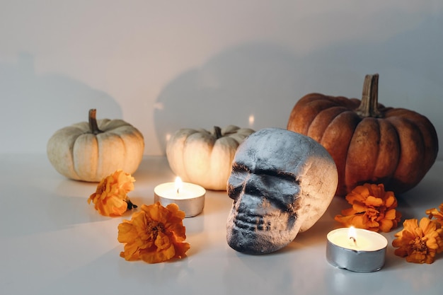 Dia de los Muertos Composition de l'autel de table du Jour des morts mexicain Tagetes orange fleurs de souci et décoration de crâne artificiel humain Bougies allumées et citrouilles Concept d'automne d'Halloween