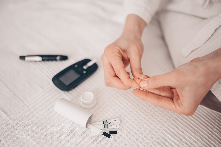 Photo diabète vérifiant la glycémie. femme à l'aide de lancette et glucomètre numérique à la maison. médecine, diabète de régime, concept de soins de santé - mains féminines avec glucomètre vérifiant le niveau de glucose corporel