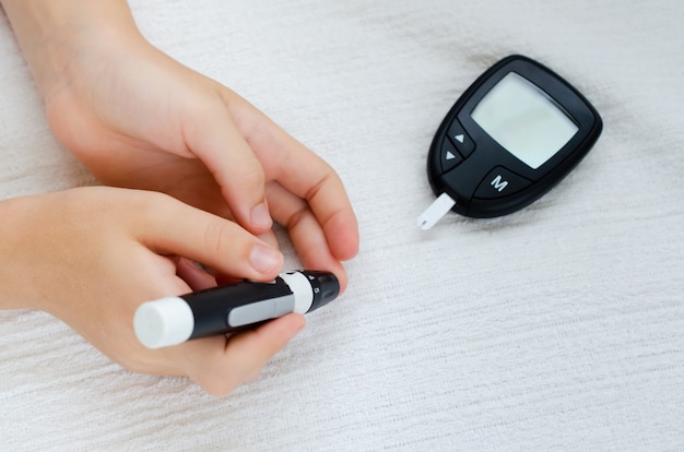 Diabète vérifiant le taux de sucre dans le sang de l'enfant à l'aide d'un lancelet et d'un glucomètre à la maison