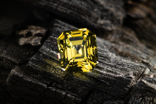 Un diamant jaune est posé sur un morceau de bois.