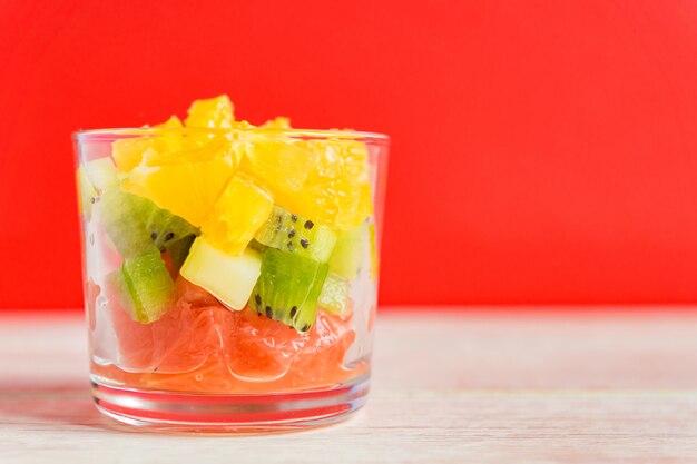 Diète Mélange de fruits frais savoureux dans un bocal en verre. Oranges juteuses, kiwis et pamplemousses hachés.