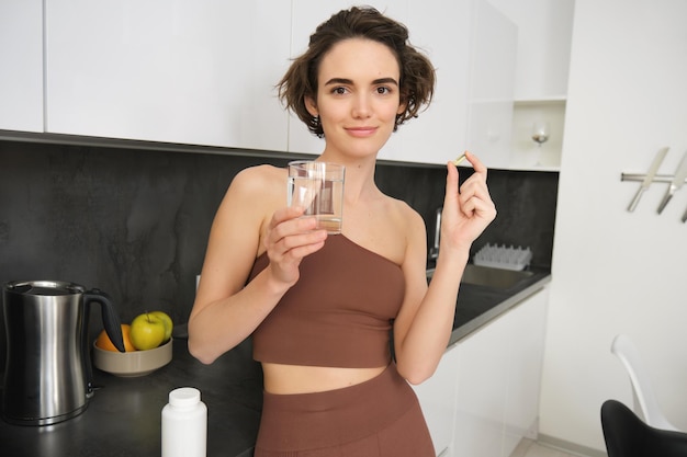 Diète nutrition alimentation saine style de vie de près de femme souriante heureuse prenant la pilule avec le foie de morue o