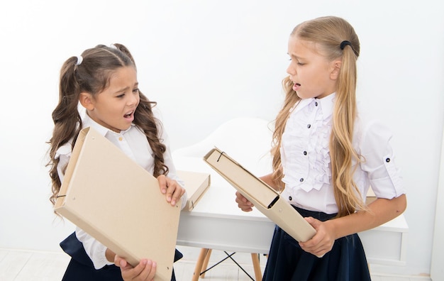 Différend de petites filles se battent avec des dossiers en classe. Querelle ou dispute de petits enfants à l'école.