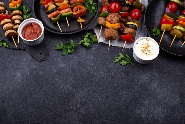 Différentes brochettes grillées avec viande, champignons, saucisses et légumes sur des brochettes