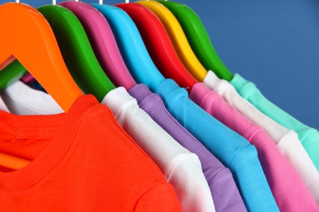 Différentes chemises sur des cintres colorés sur fond bleu