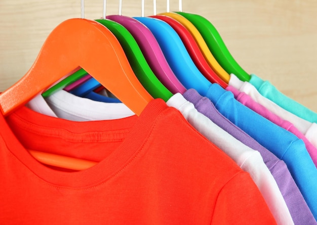 Photo différentes chemises sur des cintres colorés sur fond clair