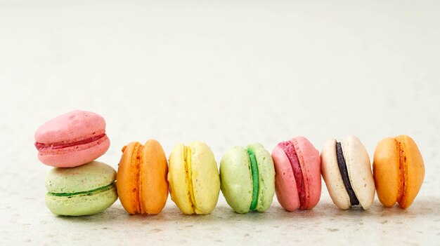 Différentes couleurs Mini macaron sur fond crème Copiez l'espace pour le texte