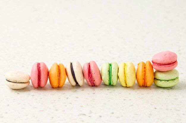 Différentes couleurs Mini macaron sur fond crème Copiez l'espace pour le texte