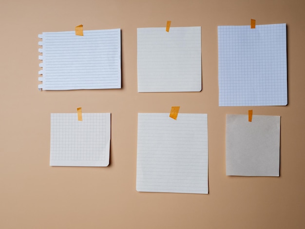 Différentes feuilles de papier vierges collées sur un fond beige