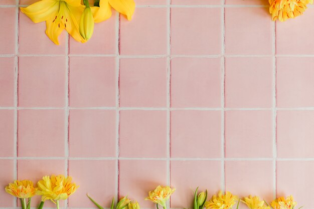 Différentes fleurs jaunes sur fond de carrelage rose