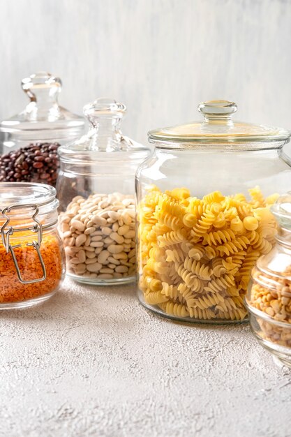 Différentes légumineuses dans des bocaux en verre : pois chiches, pâtes, haricots, pois, lentilles. Stockage zéro déchet, sans plastique.