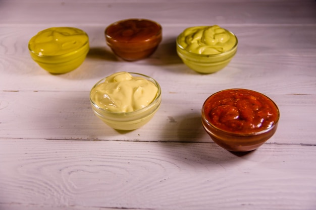 Différentes sauces dans des bols en verre sur une table en bois