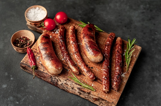 Différentes saucisses grillées aux épices et au romarin, sur une table en pierre prête à manger