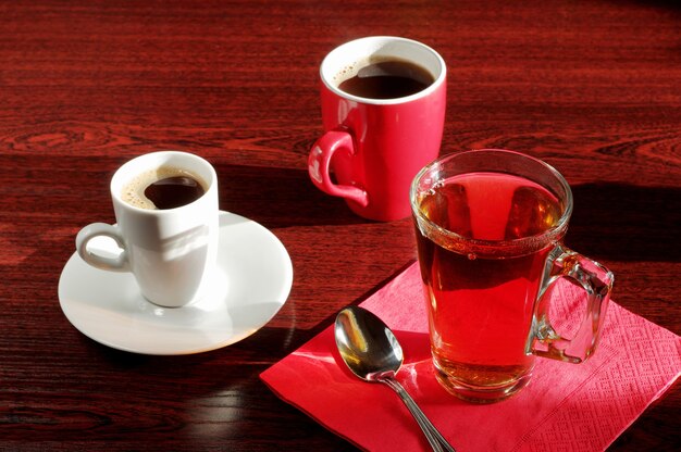 Photo différentes tasses de thé et de café sur une table en bois au soleil