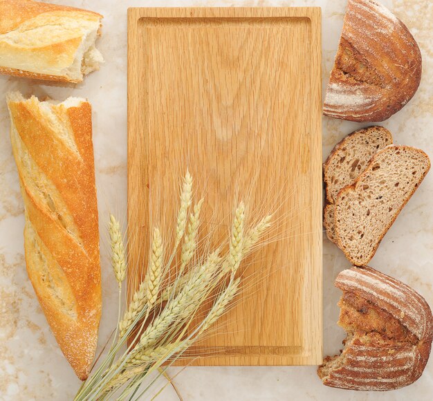 Différentes variétés de pain et d'épis de blé sur une planche de bois