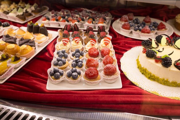 Différents beaux gâteaux savoureux colorés sur une vitrine au café