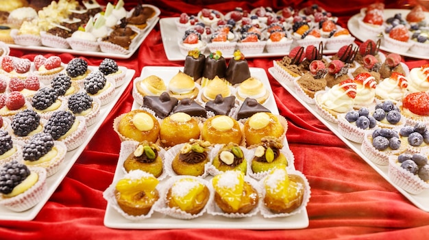 Différents beaux gâteaux savoureux colorés sur une vitrine au café