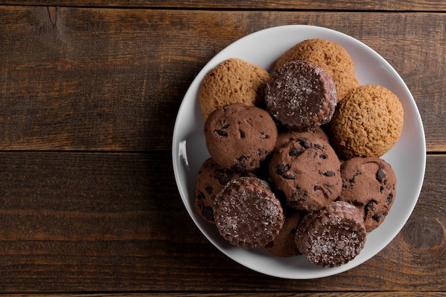 Différents biscuits savoureux sur une assiette sur une table en bois marron. vue de dessus avec espace pour inscription