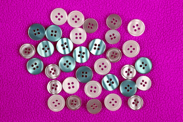 Différents boutons de nacre sur un tissu rose. Vêtements & Accessoires