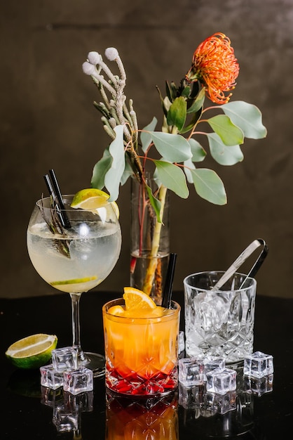 Photo différents cocktails dans des verres avec de la glace sur le fond sombre