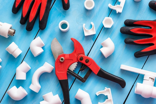 Photo différents coins, adaptateurs et raccords avec des gants et un coupe-tube pour tubes en plastique.