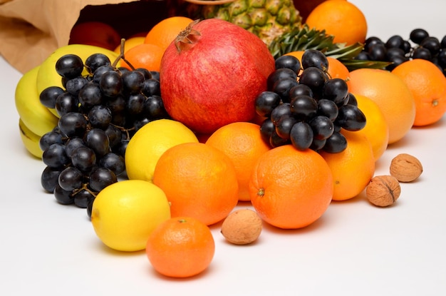 Différents fruits frais sortent d'un sac en papier sur fond blanc