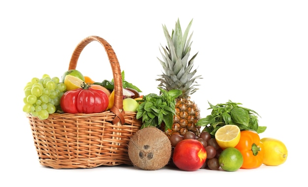Différents fruits et légumes frais dans un panier en osier isolé sur blanc