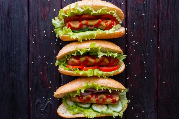 Différents hot-dogs sur un fond en bois noir