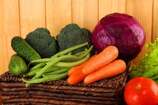 Différents légumes sur panier sur fond de bois