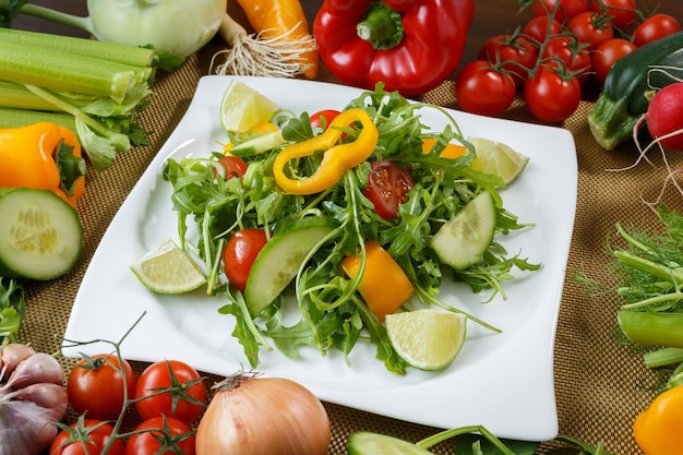 Différents légumes et salade avec légumes-feuilles et tomates cerises sur plaque blanche