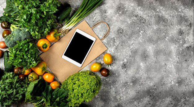 Différents légumes avec tablette et sac en papier. Bannière Vue de dessus avec place pour le texte.