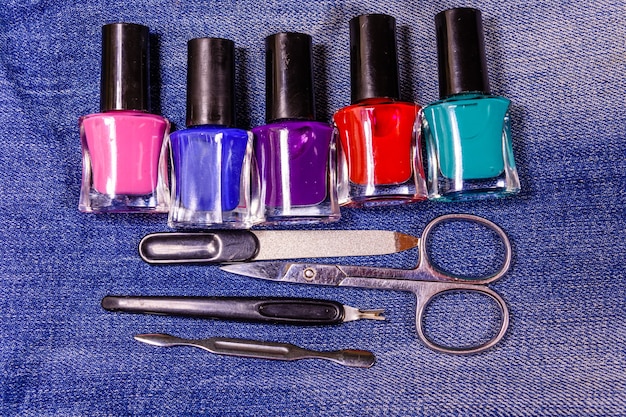 Différents outils de manucure et vernis à ongles sur le jean bleu. Vue de dessus