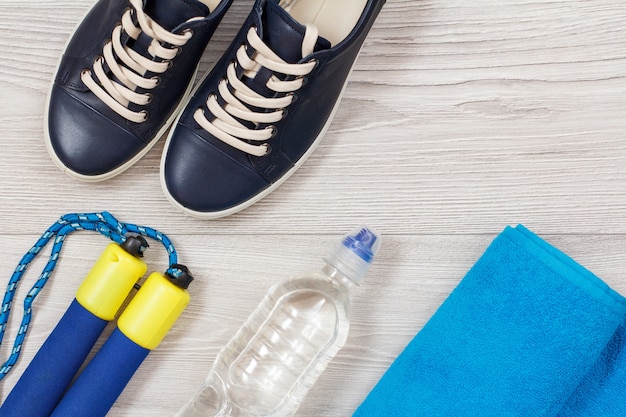 Différents outils de remise en forme avec bouteille d'eau dans la chambre ou la salle de sport sur sol gris