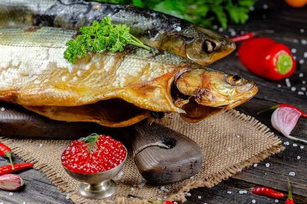 différents poissons de rivière fumés par la mer se trouvent sur un rustk vissé sur une planche à découper et une table, les cordes,